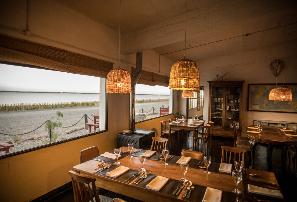 des tables, des chaisses et des couverts dans le restaurante de Bahía Bustamante Lodge