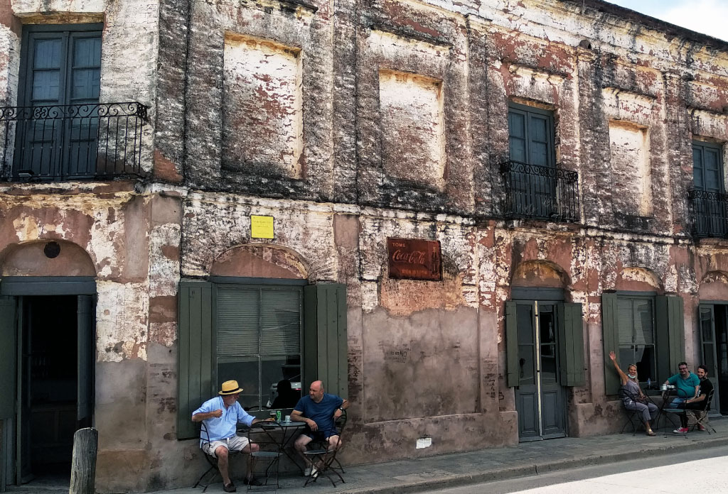 Boliche de Bessonart à San Antonio de Areco. Un ancien bâtiment de deux étages avec des murs de briques et des gens buvant du café, assis, à la porte.