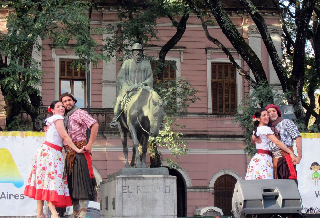 Devant deux couples embrassés après avoir dansé, elles sont habillées comme des compatriotes. Derrière le monument qui rend hommage au Resero : un homme à cheval.