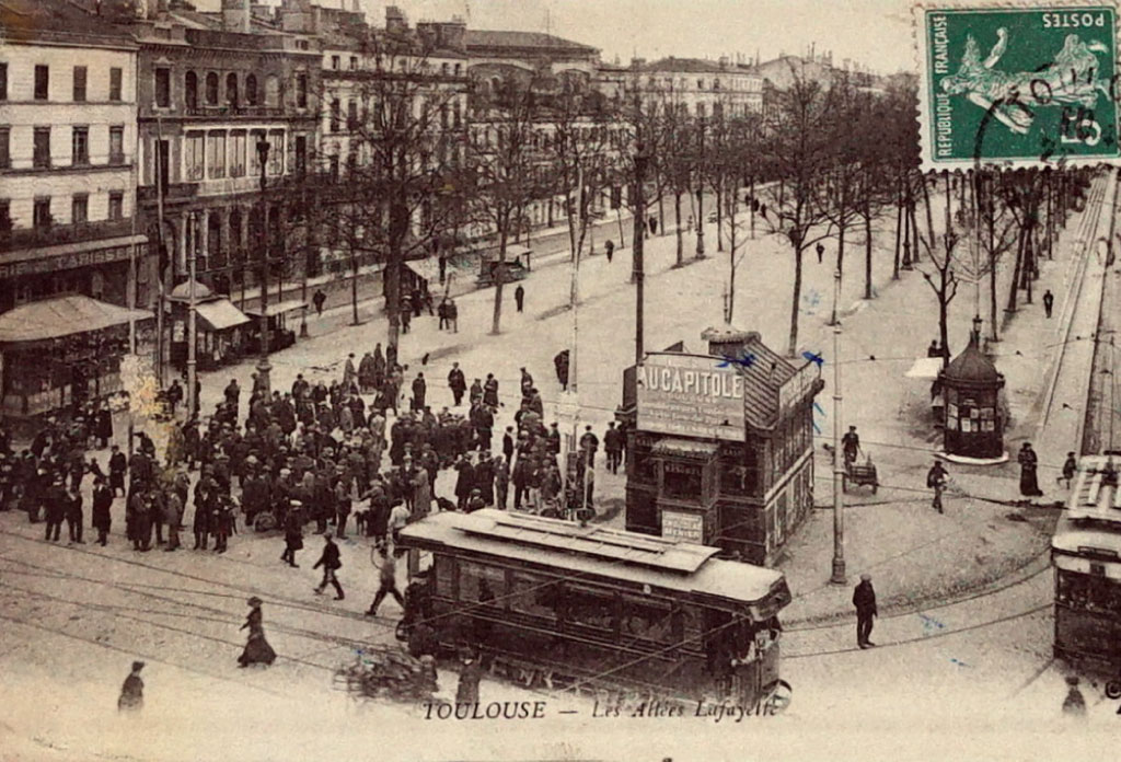Photo d’une ancienne carte postale de 1915 de Toulouse. Il y a une place avec de tranway et des personnes.