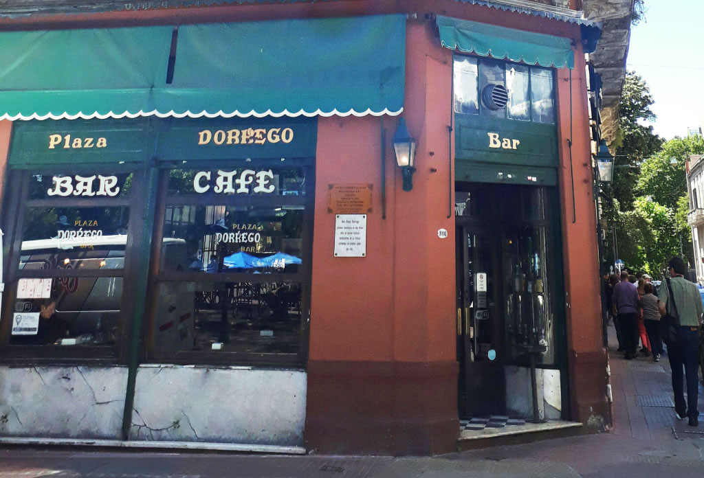 Façade du remarquable bar Plaza Dorrego avec des auvents en toile verte. Les fenêtres portent l'inscription du nom du bar.