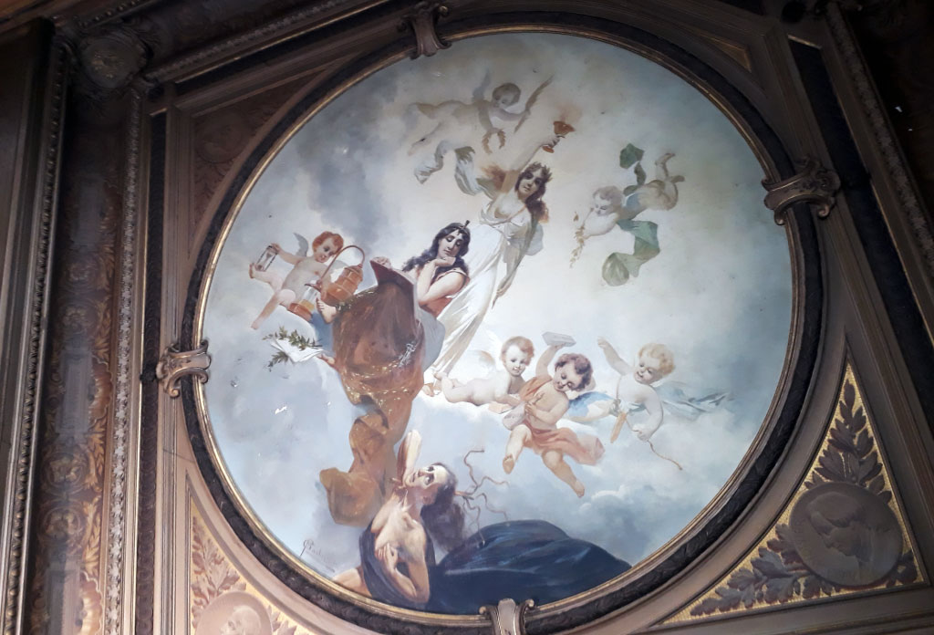Peinture murale sur le plafond dans le Pharmacie La Estrella. Il y a une femme qui représente la pharmacie et une autre femme qui représente la maladie et à son tour il y a des chérubins.