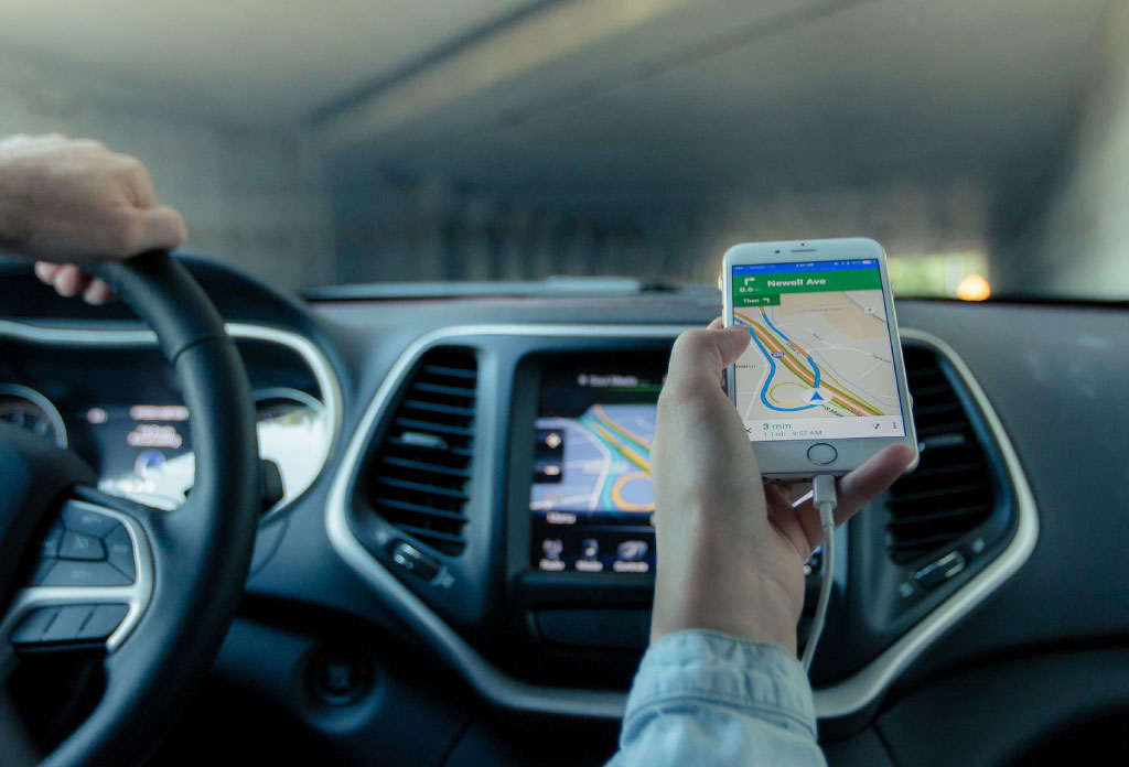Dans une voiture une personne porte un telehpone portable qui montre une carte gps.