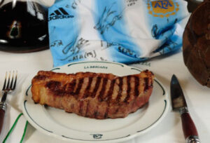 Dans une assiette avec des couverts sur les côtés. Derrière un maillot de football argentin.