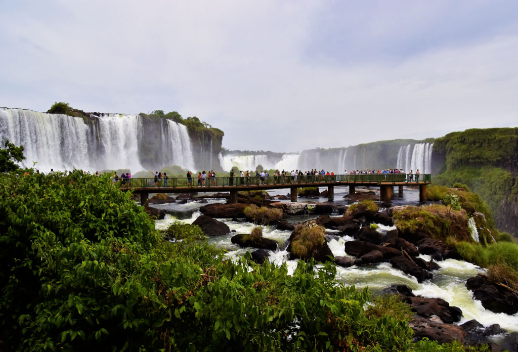 photo panoramique des chutes d'Iguazu et des gens qui se promènent sur les passerelles proches des chutes
