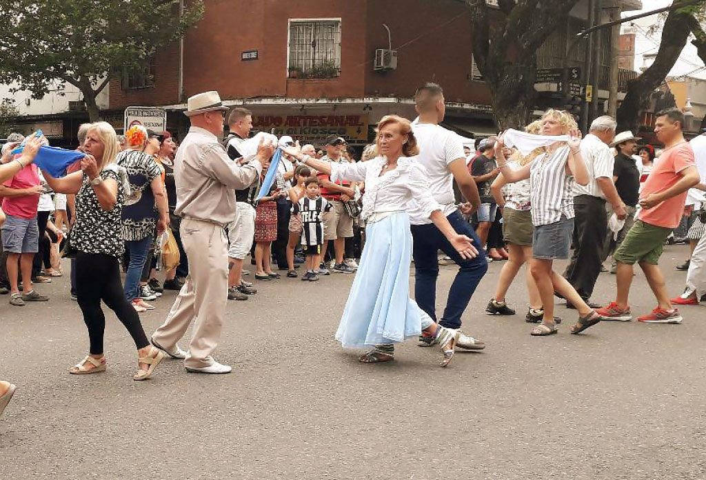 deux personnes habillées comme des paysans qui dansent dans la rue.