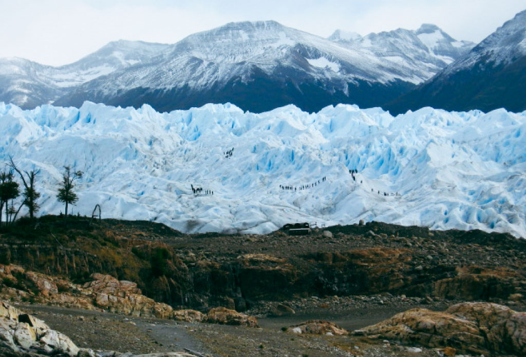 Les gens marchent sur le glacier Perito Moreno et devant les rochers.
