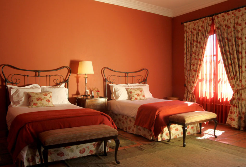 chambre d’hôtel avec deux lits, une fenêtre, fauteuil et lampe