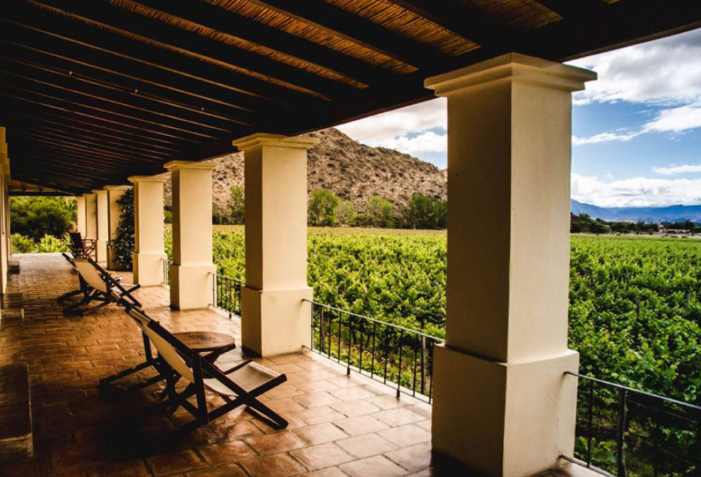 Balcon d’une chambre de l’hôtel Viñas de Cafayate. Deux chaises longues sont placées à côté du balcon en observant les vignobles.