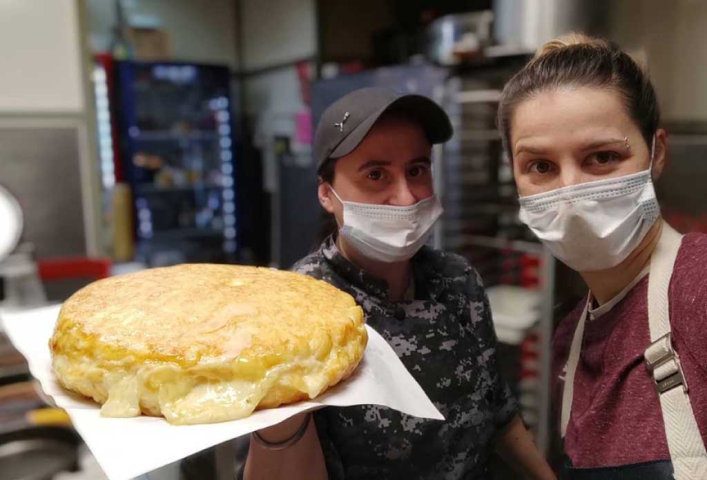 Deux femmes, Pato et Romina, montrant une omelette espagnole avec beaucoup de fromage à la caméra