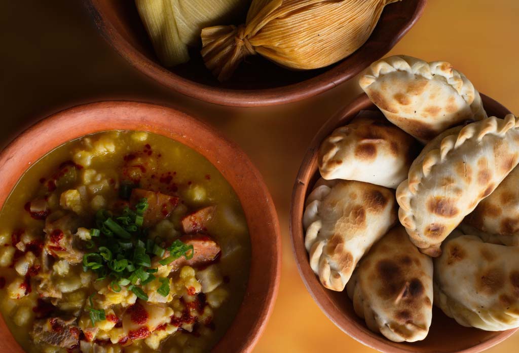 Photo avec différents plats typiques de la gastronomie de la Quebrada de Humahuaca : locro, empanadas, tamales.