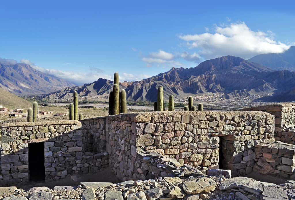 Plusieurs maisons en pierre appartenant à la forteresse Pucará de Tilcara dans la province de Jujuy, en Argentine. Derrière on voit des montagnes.