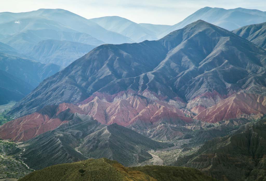 Photo d’une Quebrada dans le nord de l’Argentine, semblable à une vallée entourée de montagnes de différentes couleurs