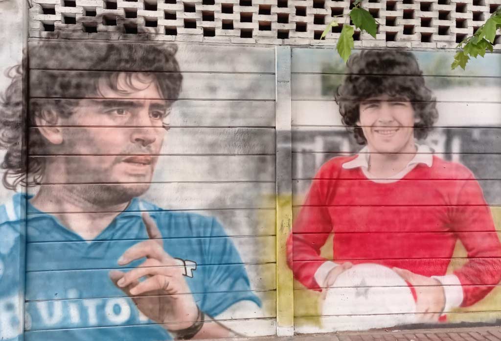 mur d’un stade de football avec différentes peintures qui recréent la vie de Maradona