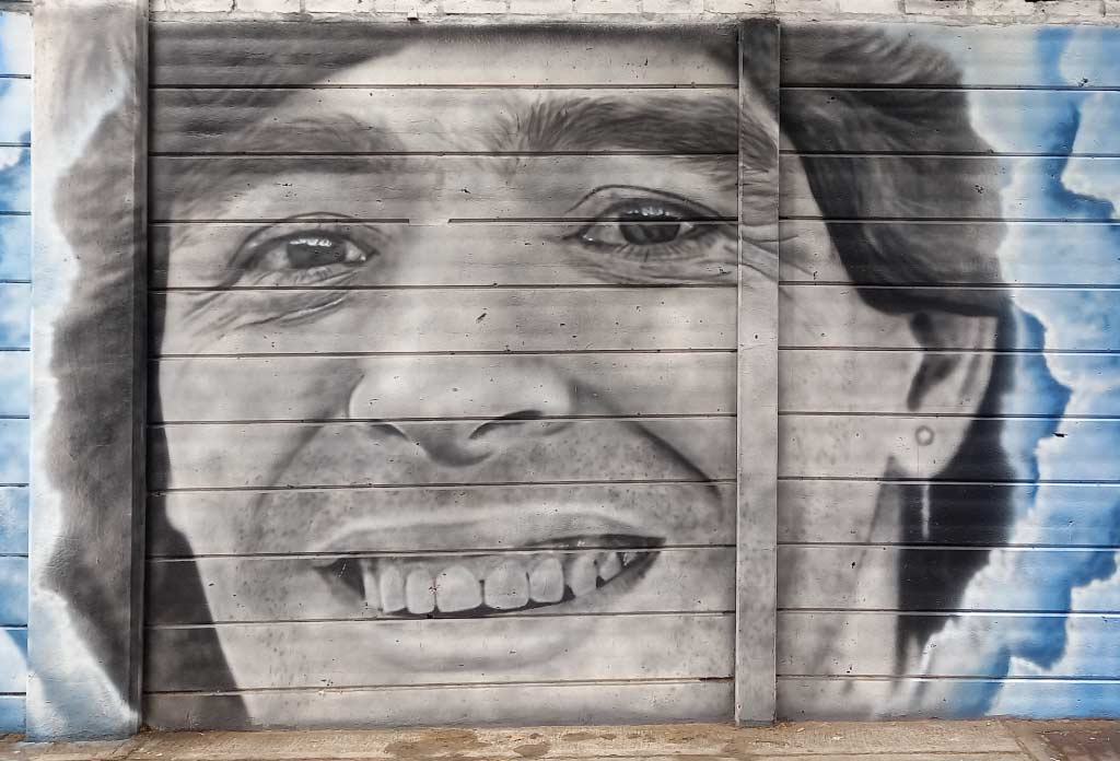 mur d’un stade de football avec différentes peintures qui recréent la vie de Maradona