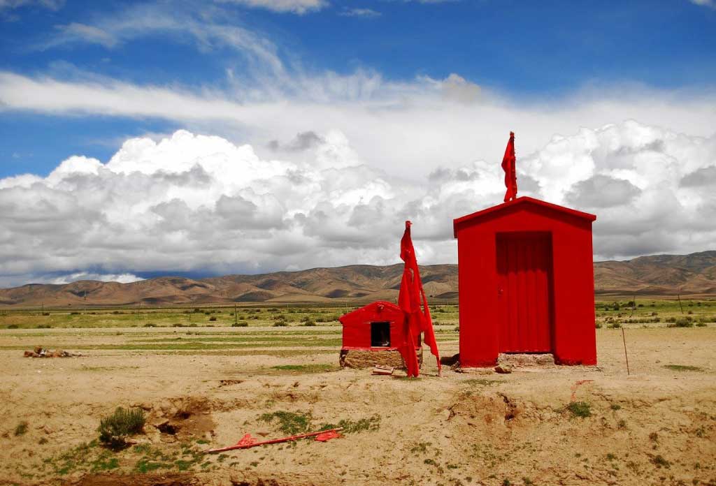 Une petite case rouge avec un drapeau au milieu d’un paysage semi-désertique qui rend hommage au Gauchito Gil
