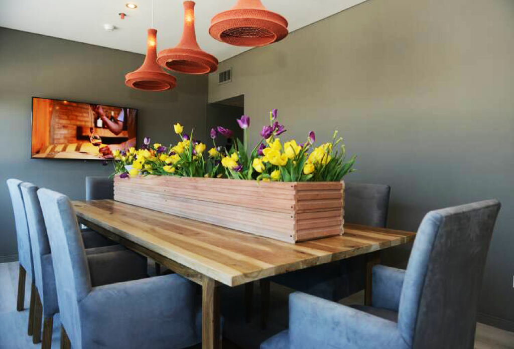 une table avec des chaises autour et sur la table il y a de grands pots avec des fleurs
