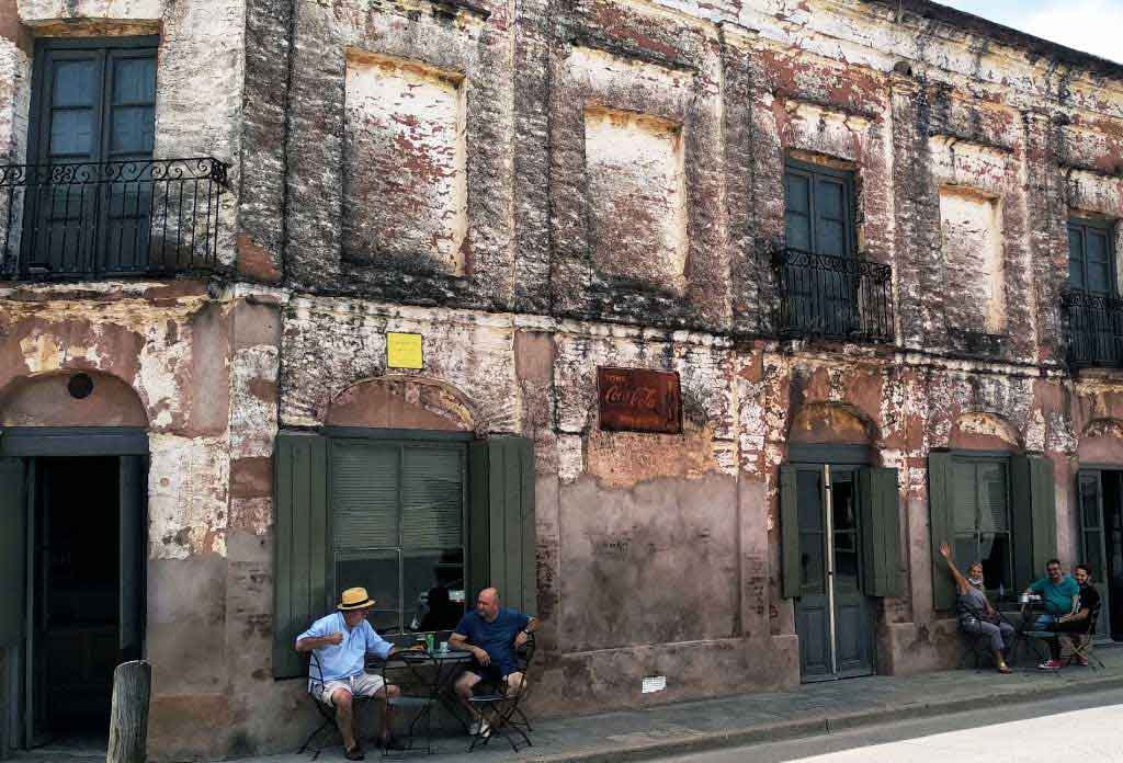 façade d’un vieux bar avec deux personnes buvant un café